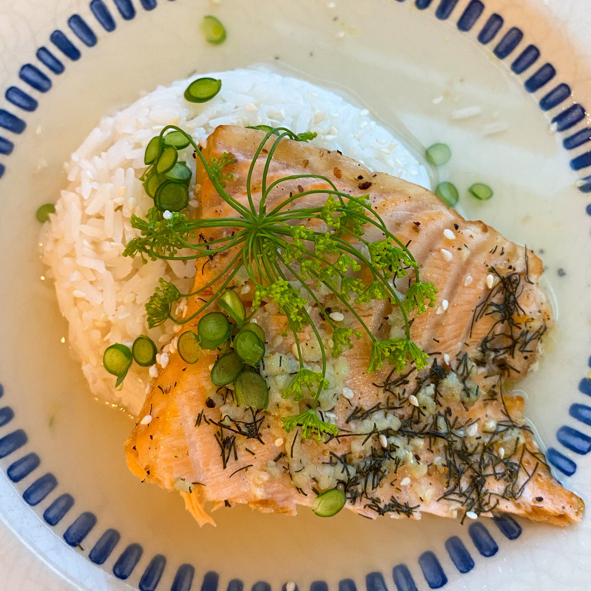 salmon over a ball of rice garnished with scallions and dill