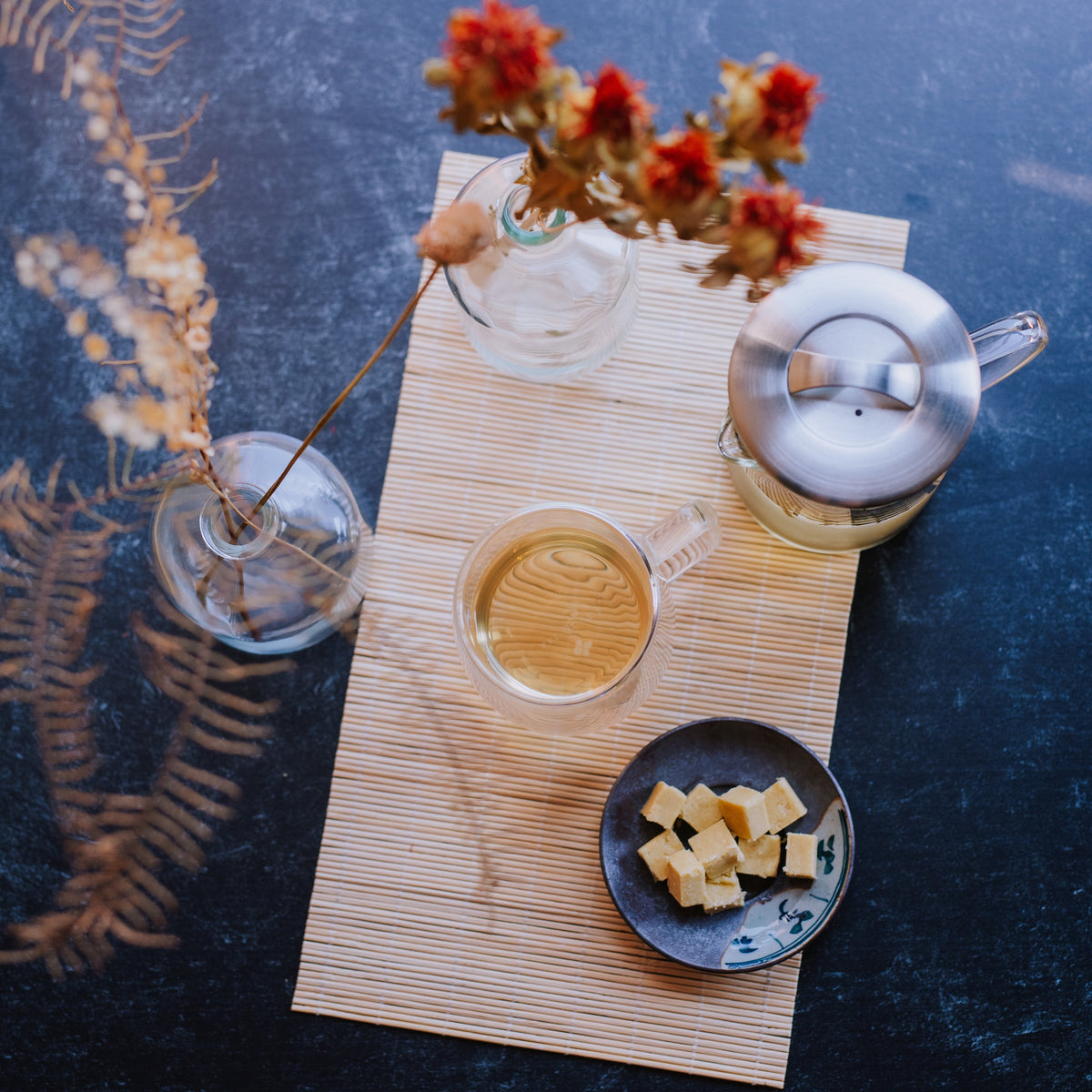 top down view of green tea in a glass mug with glass infuser and mung bean cakes on a plate