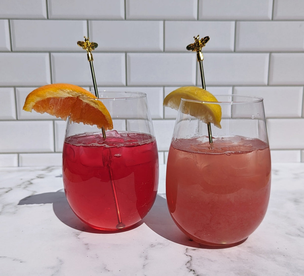two tea spritzes with garnish and bee stir sticks