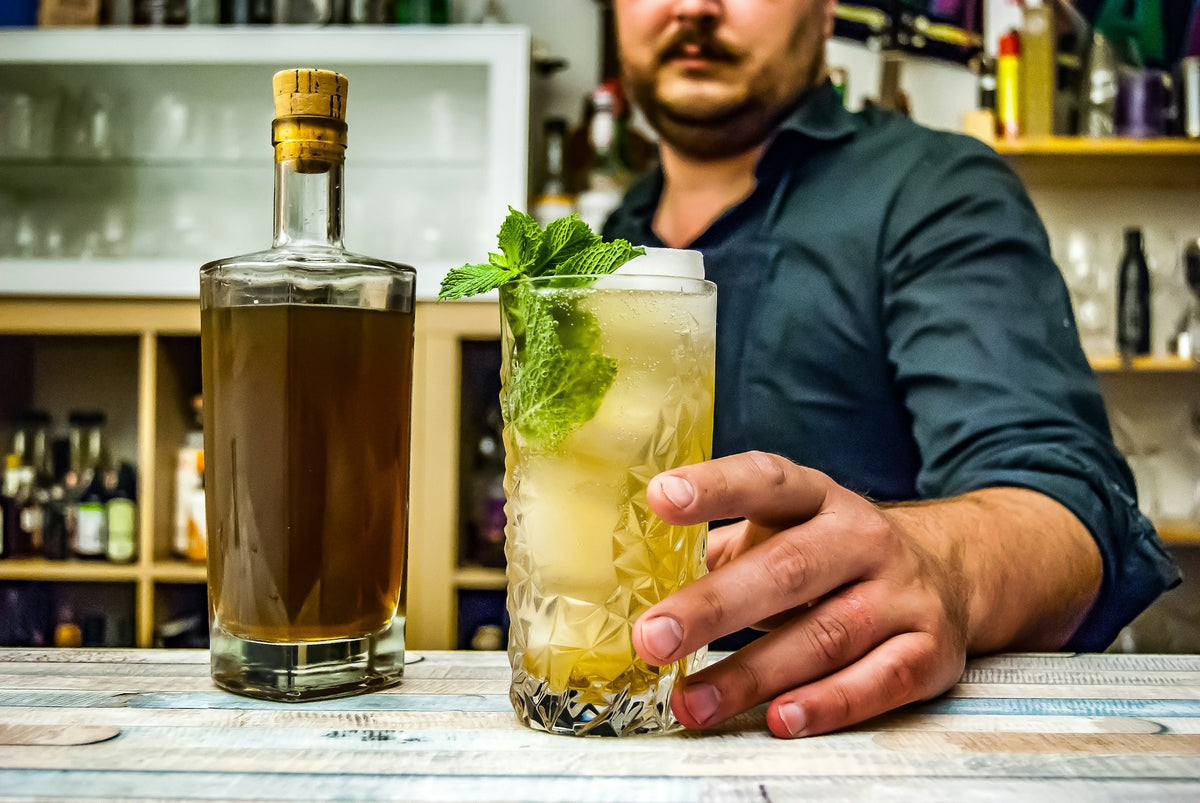 man presenting mint julep cocktail