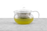 A glass teapot with a metal infuser filled with green tea.