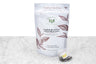English Breakfast tea sachets packaging and example sachet. A small pyramid tea sachet with visible black tea leaves sits next to a pouch reading "English Breakfast Assam Banaspaty Organic Black Tea. 15 Biodegradable & Compostable Tea Bags."