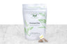 Genmai Cha green tea sachets packaging and example sachet. A small pyramid tea sachet with visible green tea leaves and brown toasted rice sits next to a pouch reading "Genmai Chai Organic Green Tea. 15 Biodegradable & Compostable Tea Bags."