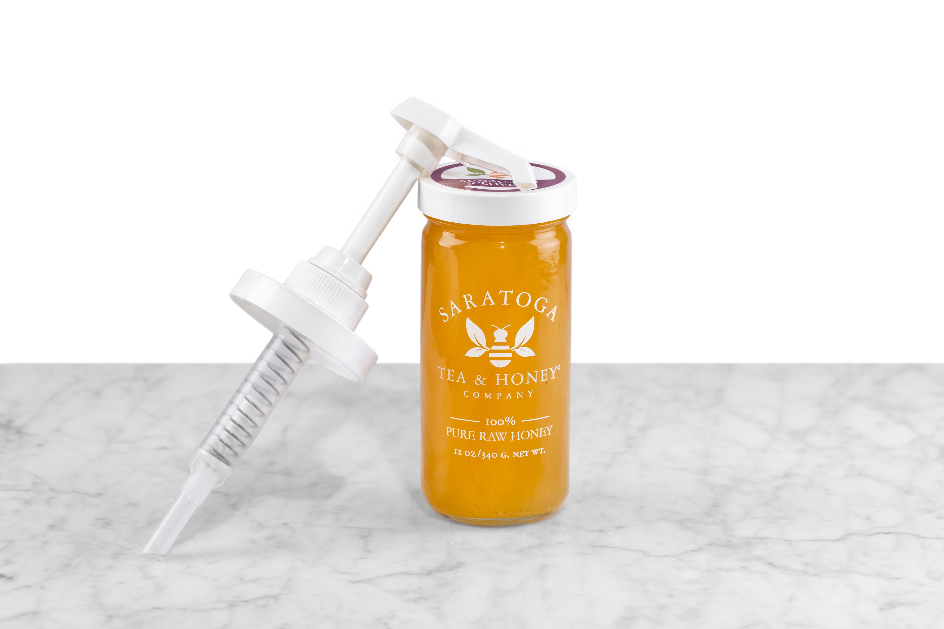 white plastic honey pump leaning against jar of Saratoga Tea & Honey Co. golden hued honey
