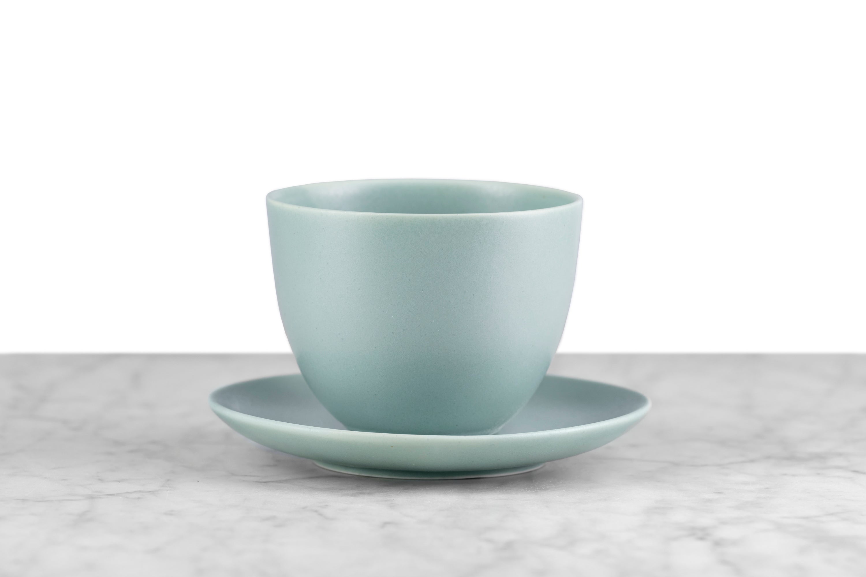 kinto pebble modern Japanese teaware moss green handleless cup and saucer on marble with white background