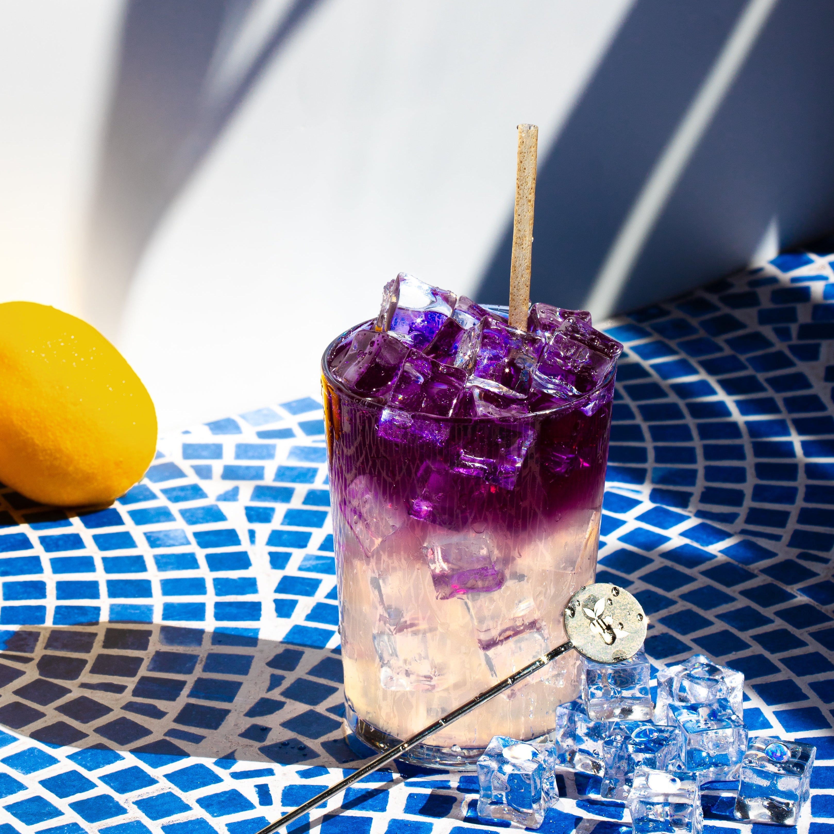 Lavender Lemonade in a clear glass made with homemade lemonade on the bottom and iced Karner Blue Lavender tea on the top. The blue Karner Blue Lavender tea has changed from blue to vibrant purple after coming into contact with the citrus in the lemonade.