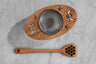 top down view of wooden and metal tea infuser and wooden honey dipper with bee motif