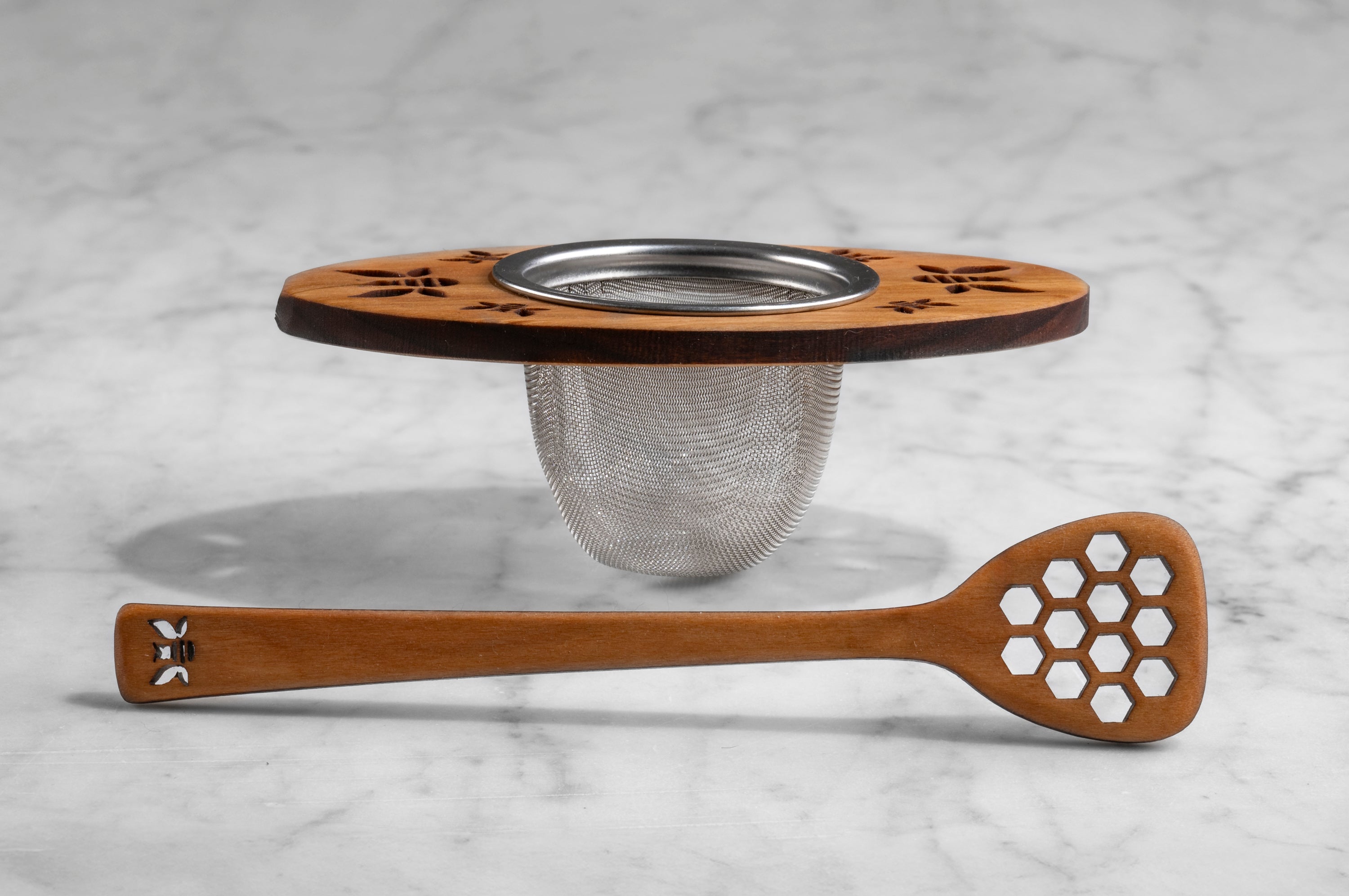 side view of wooden tea infuser and wooden honey dipper with bee motif