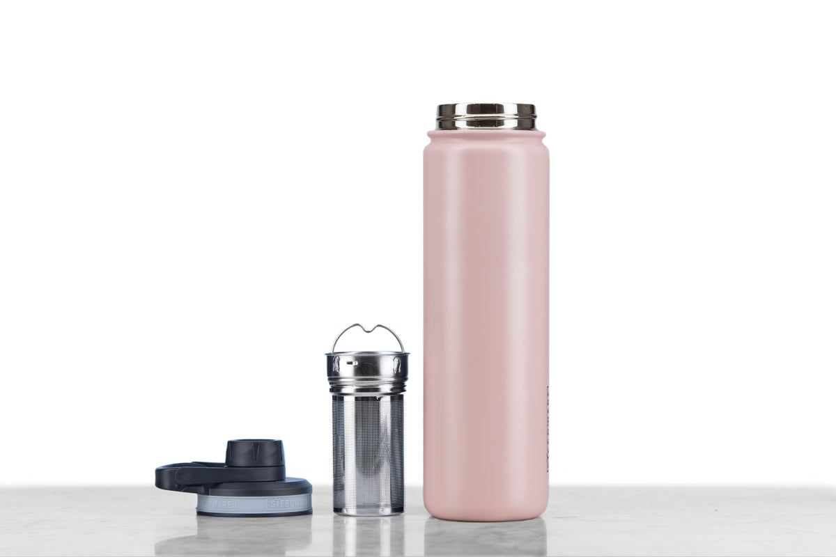 A pink tea tumbler with a stainless steel infuser basket.