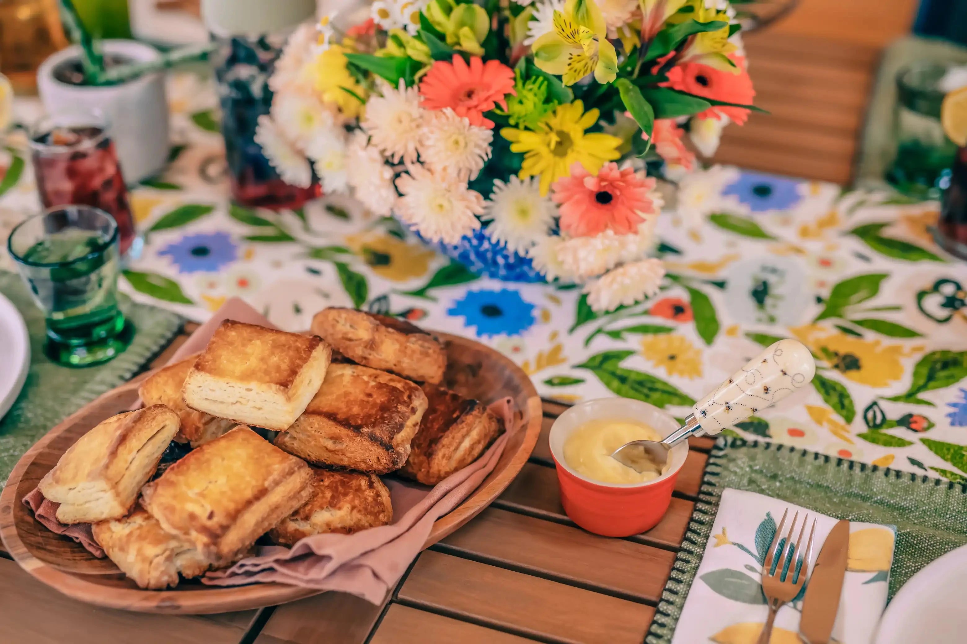 honey biscuits on a wooden platter next to a dish of honey butter with a bee knife 