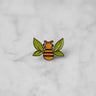 "Tea Bee" silver enamel pin with green tea leaf wings and orange bee body centered on marble. 
