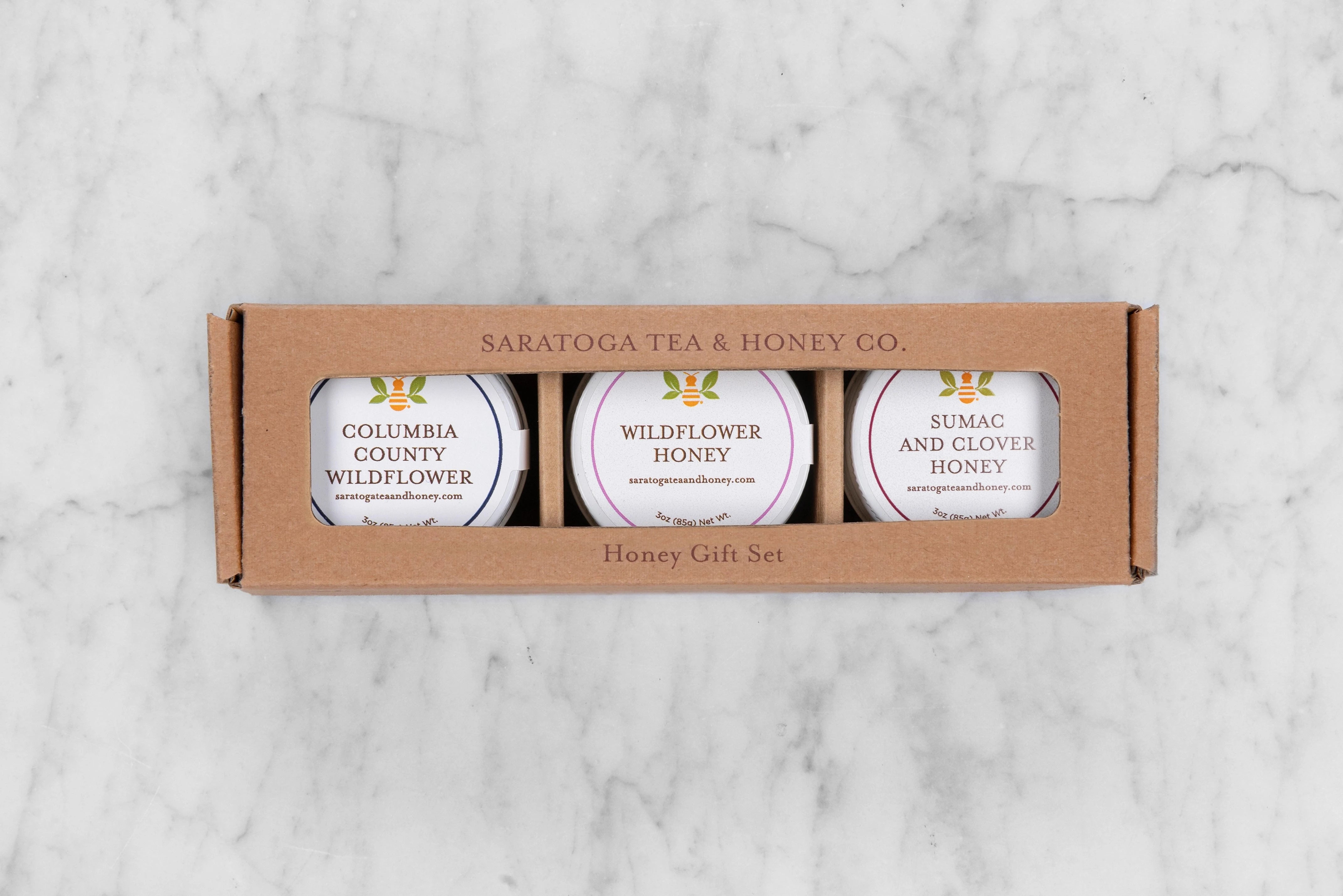 kraft box with an opening showing three mini honey jars of local Upstate NY honeys: Columbia County Wildflower, Saratoga Springs Wildflower Honey, and Sumac and Clover Honey