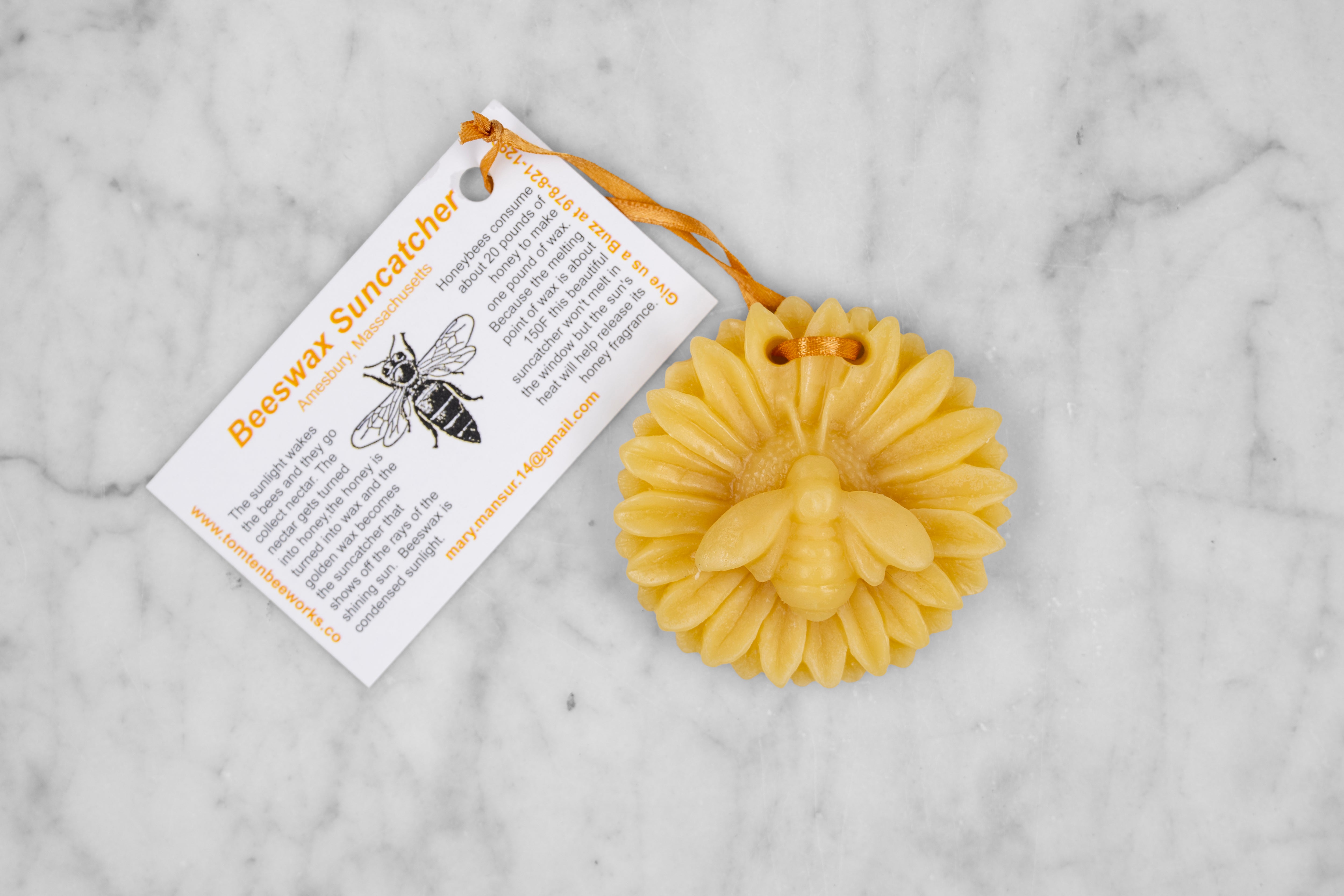 A beeswax ornament in the shape of a bee on a flower.