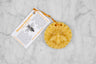 A beeswax ornament in the shape of a bee on a flower.