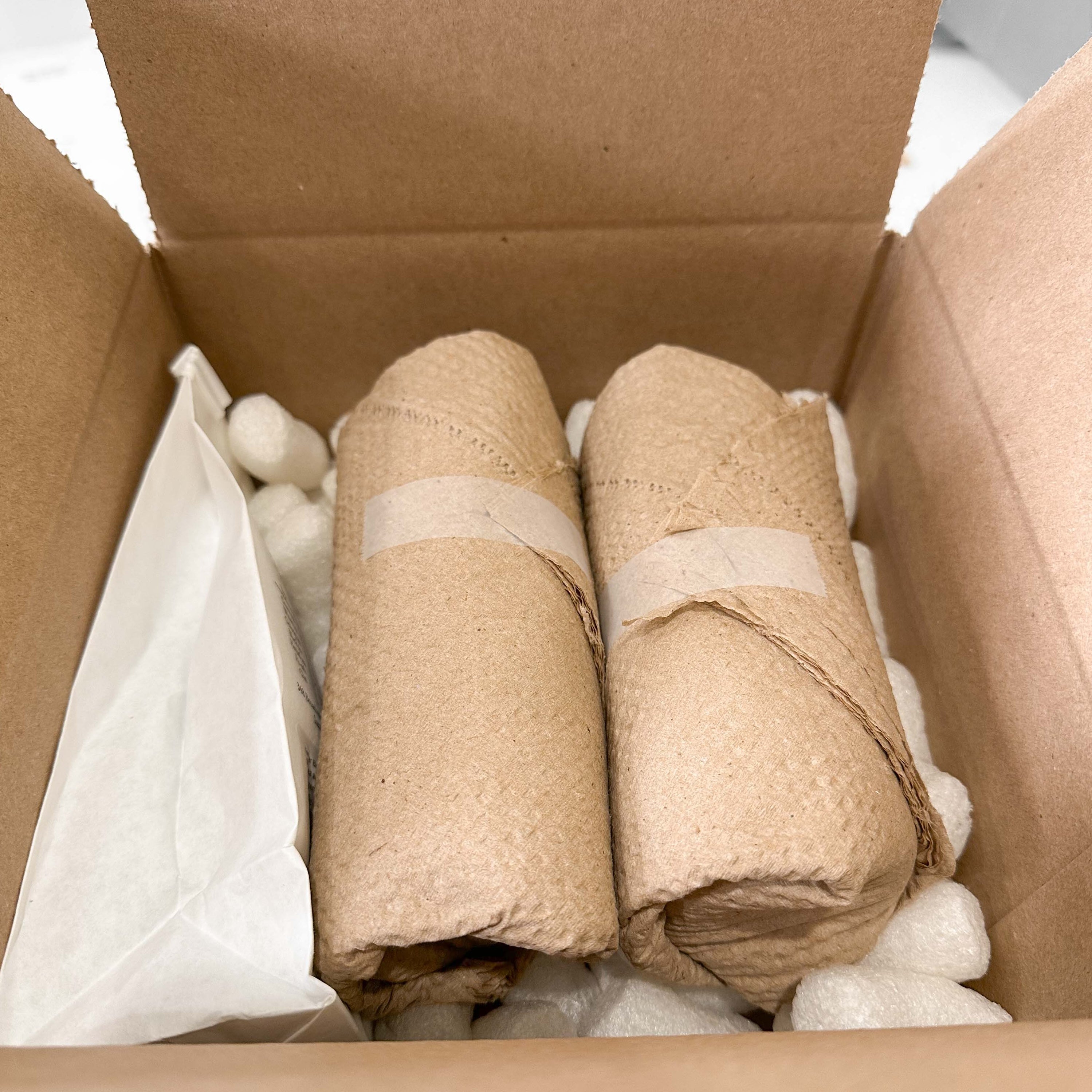 Honey jars wrapped in brown cellulose wadding in a shipping box.