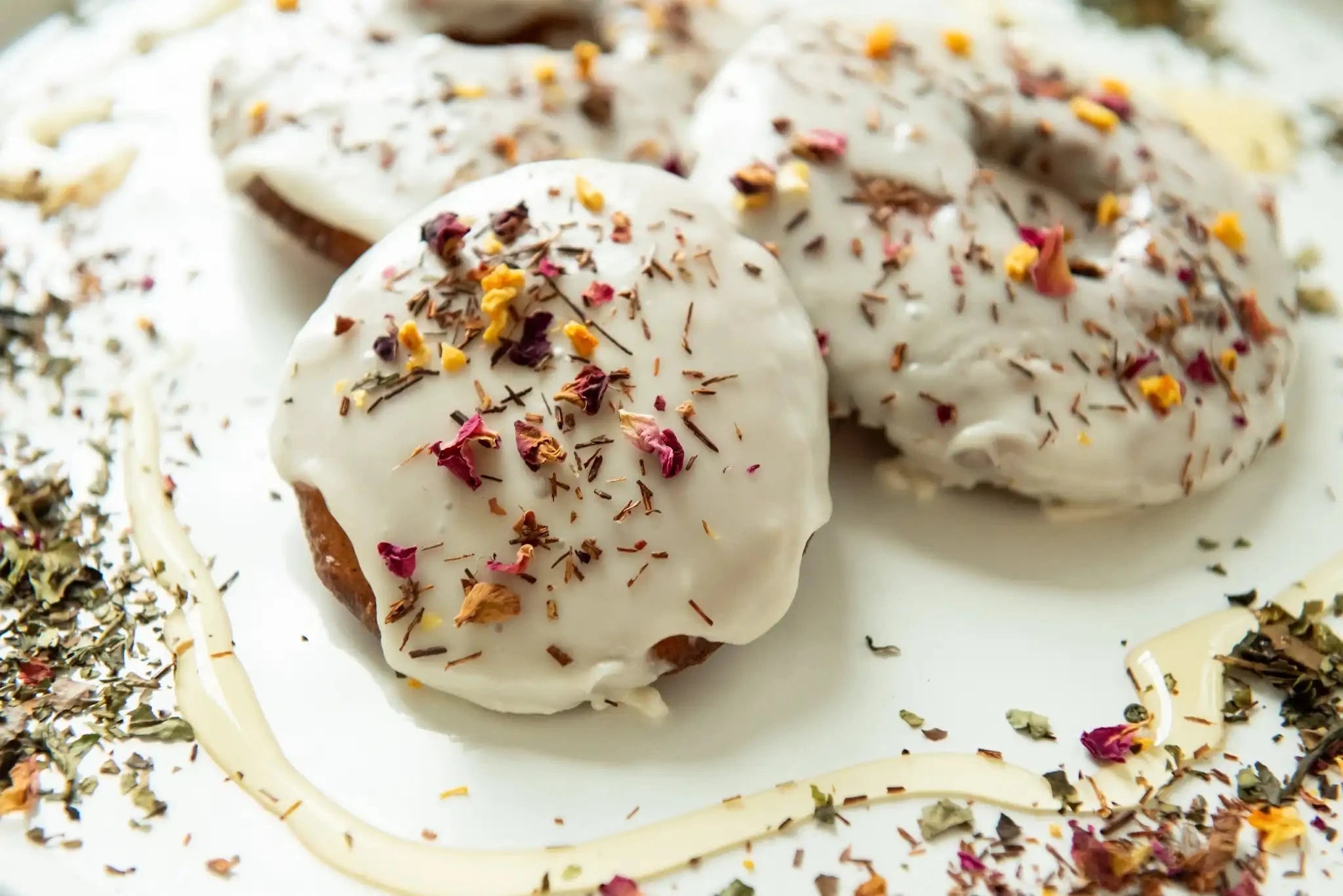sweet white peach tea and honey donuts on a white plate with honey drizzle and loose tea sprinkles