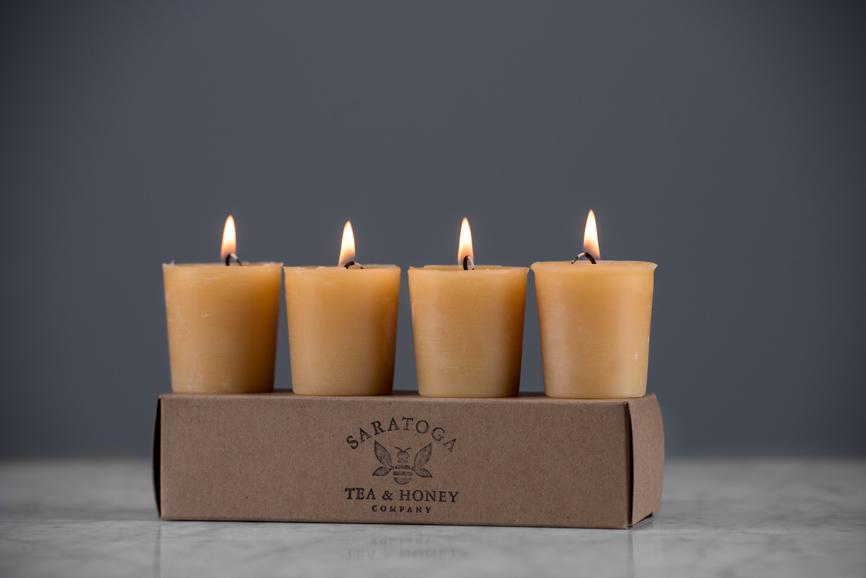lit beeswax votive candles sitting on a kraft box