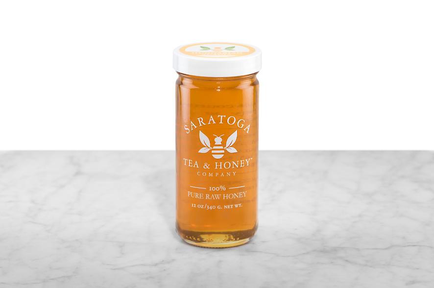 Golden Acacia Honey displayed in a 12oz cylindrical glass jar with a white lid. The logo and the words: "100% Pure Raw Honey" are printed on the jar.