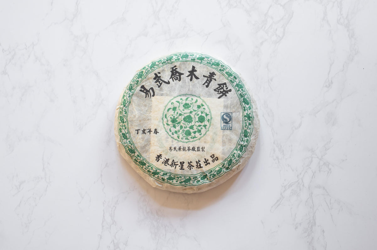 2007 Yiwu Jing Long sheng pu'er round aged tea cake wrapped in paper with Chinese characters.