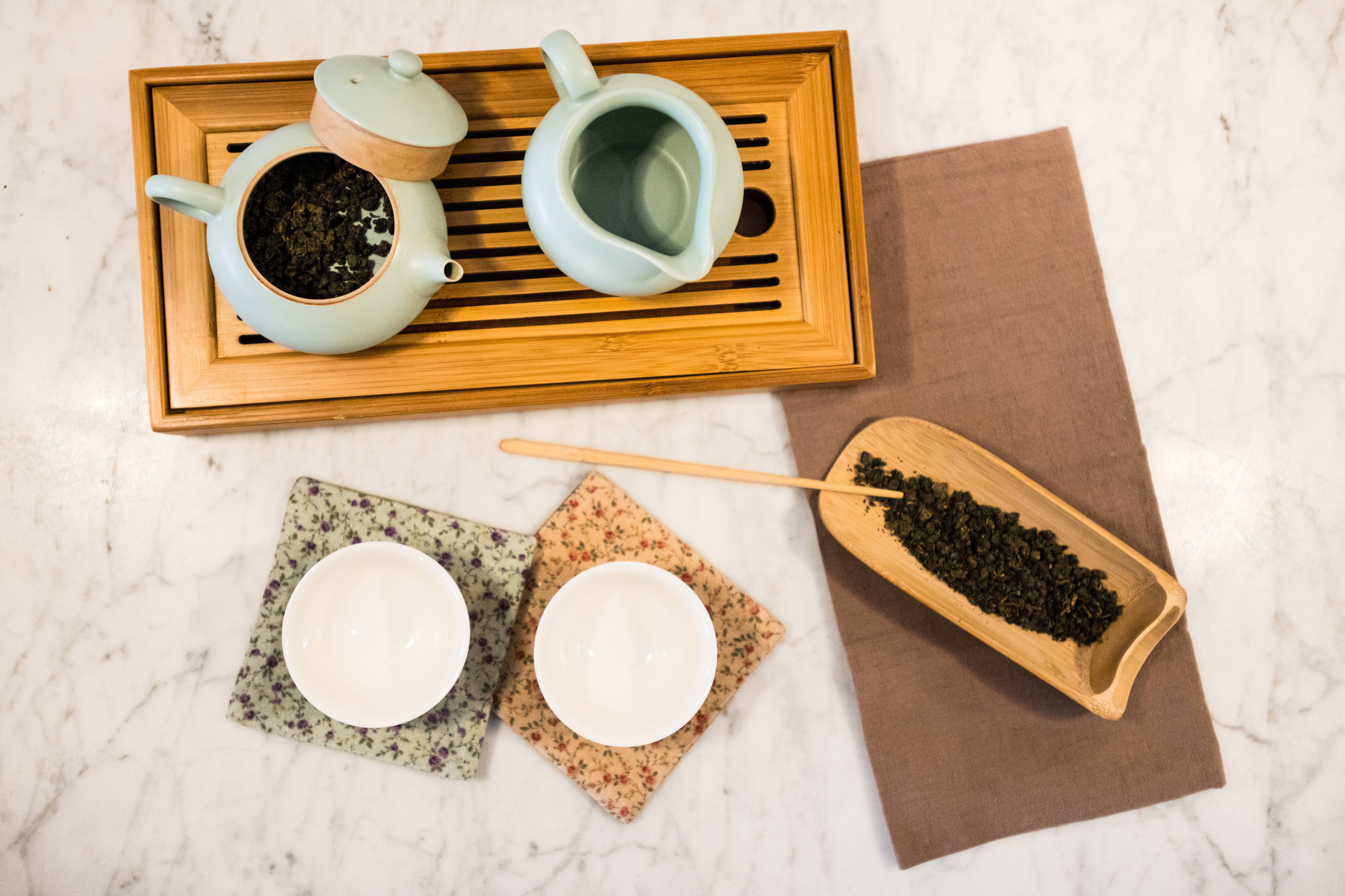 rolled Taiwanese oolong in a pancake teapot sitting on a tea boat with white cups