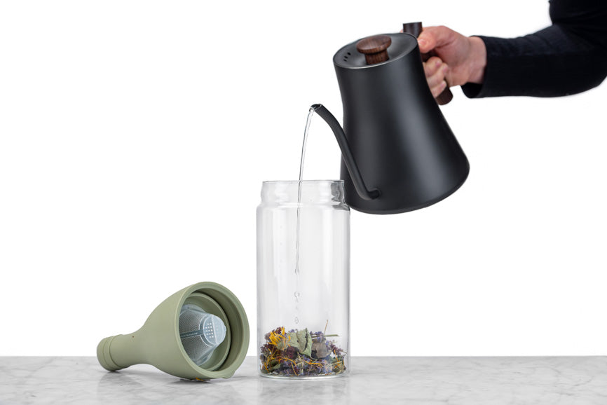 water being poured into an iced tea bottle from a gooseneck tea kettle