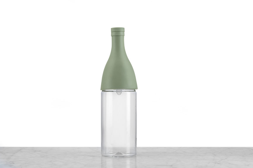 iced tea bottle with a green silicone top on a marble and white background