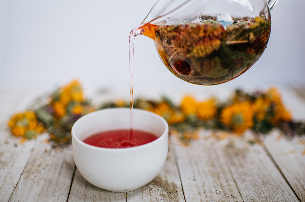 pink herbal tea poured into a white cup from a glass teapot with tranquilite